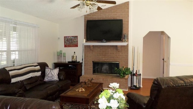 living room with hardwood / wood-style flooring, ceiling fan, lofted ceiling, and a brick fireplace