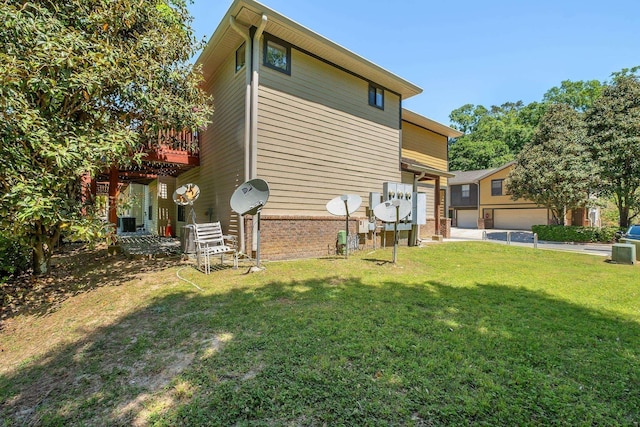 back of property with a garage, brick siding, a wooden deck, and a yard