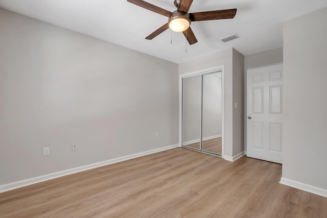 unfurnished bedroom with light wood-style floors, a closet, a ceiling fan, visible vents, and baseboards