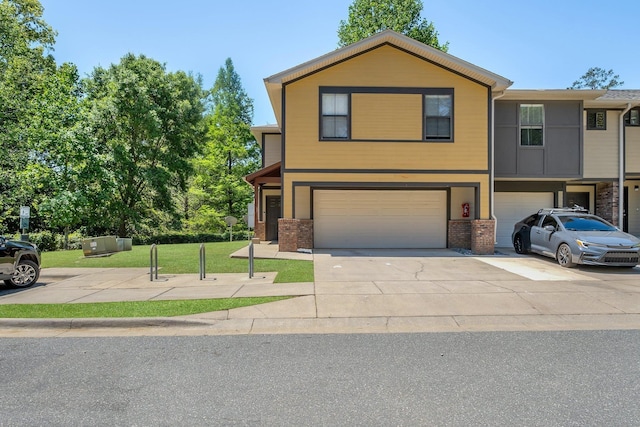 view of front of property featuring driveway, a front yard, brick siding, and an attached garage
