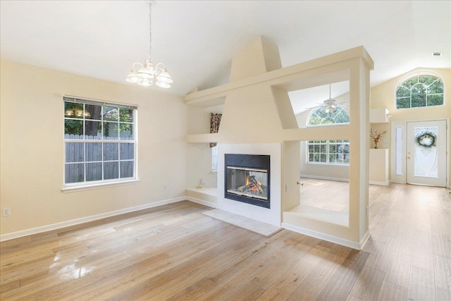 2942 Tewkesbury Trce, Tallahassee, FL 32309 - unfurnished living room featuring healthy amount of natural light, wood finished floors, a chandelier, high vaulted ceiling, and a glass covered fireplace