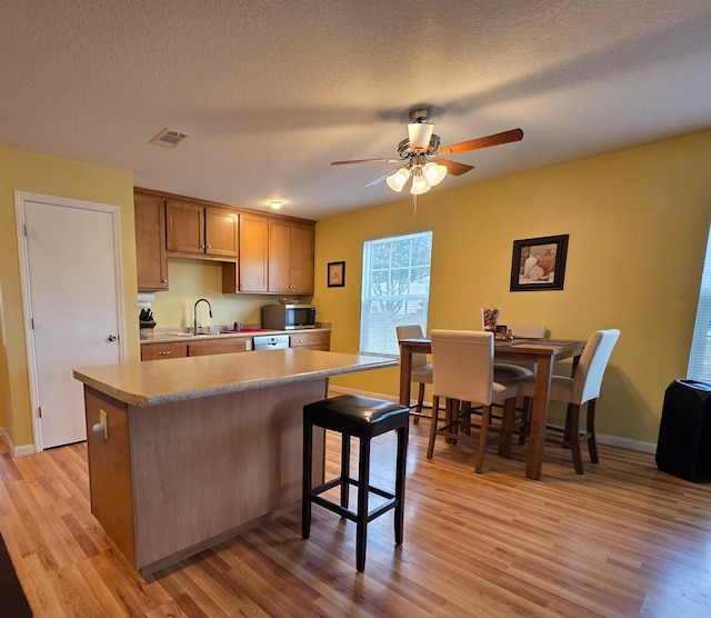 kitchen with a center island, a textured ceiling, a breakfast bar area, and light wood-type flooring