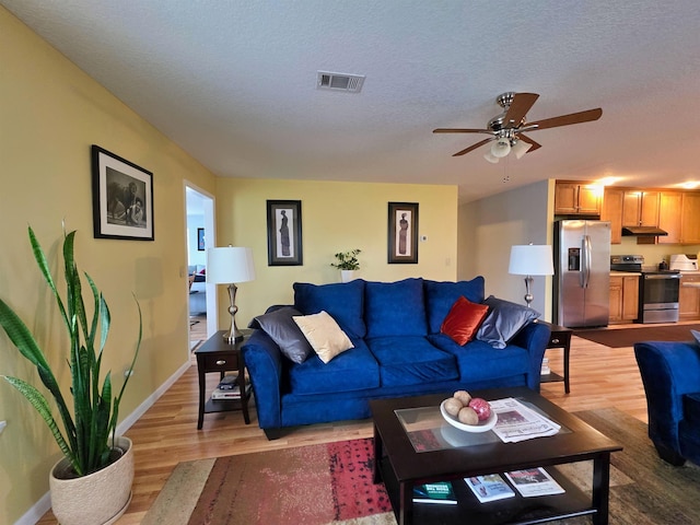 living room featuring ceiling fan, a textured ceiling, and light hardwood / wood-style flooring