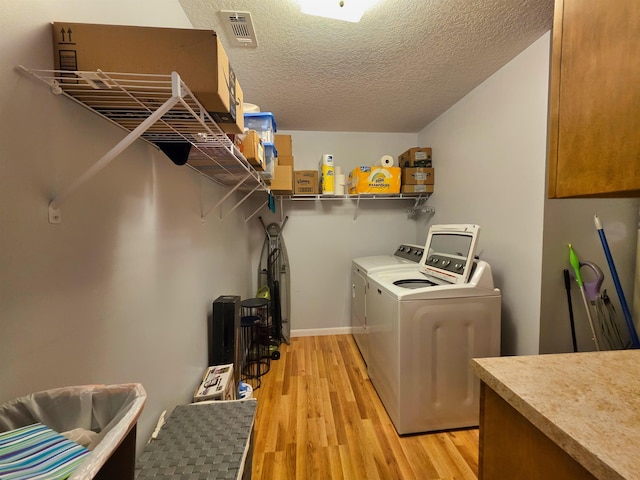 laundry area featuring light wood-type flooring, a textured ceiling, and independent washer and dryer