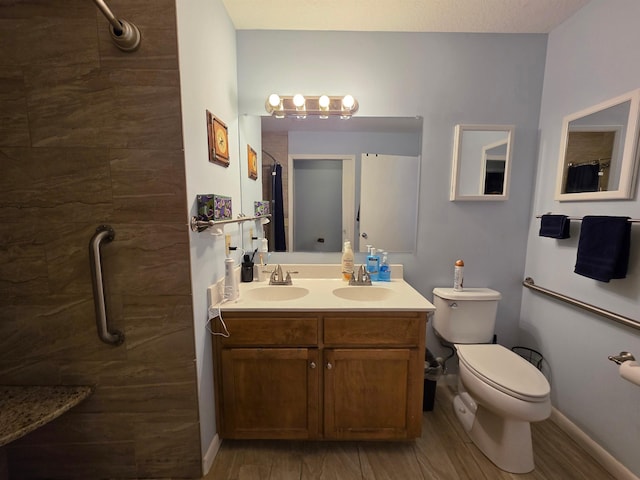 bathroom with vanity, toilet, hardwood / wood-style floors, and a tile shower