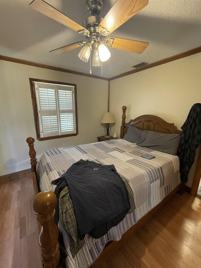 bedroom featuring visible vents, wood finished floors, and ornamental molding