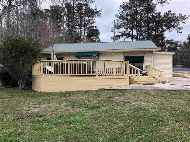 view of front of house featuring a deck, metal roof, and a front lawn