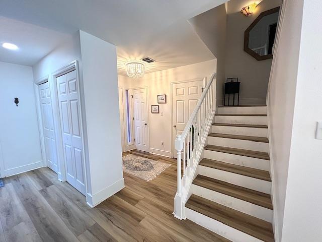 1814 Atlantis Pl, Tallahassee, FL 32303 - staircase with a chandelier, wood finished floors, and baseboards