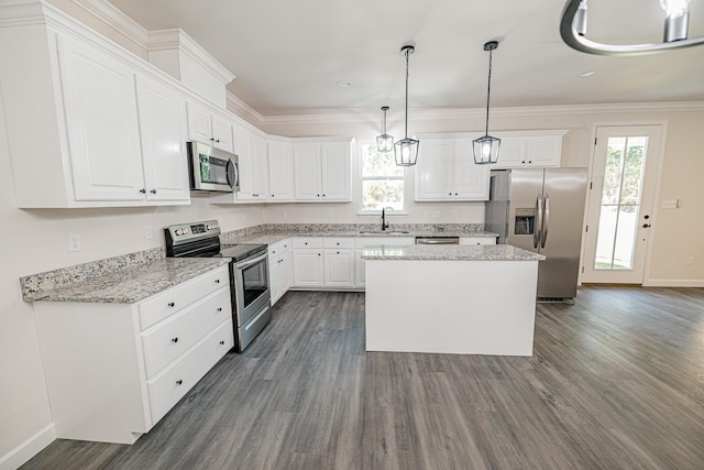 kitchen featuring white cabinets, a kitchen island, stainless steel appliances, pendant lighting, and a sink