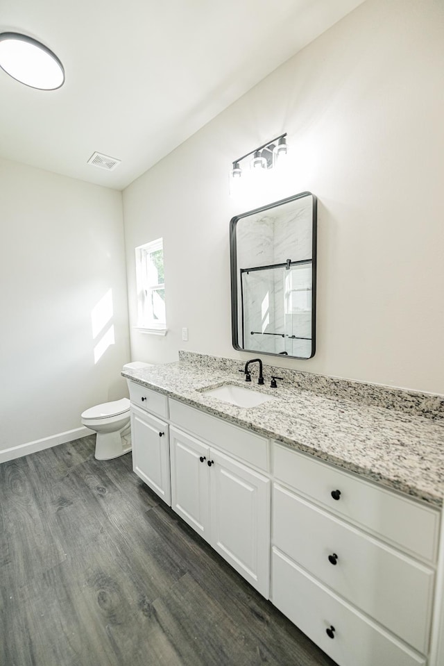 bathroom featuring a shower, visible vents, toilet, vanity, and wood finished floors