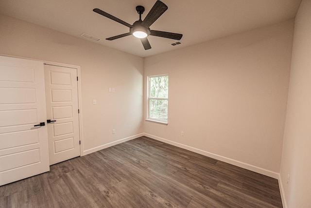 unfurnished room with ceiling fan, dark wood-type flooring, visible vents, and baseboards