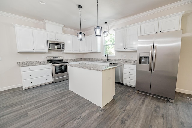 kitchen featuring a center island, white cabinetry, appliances with stainless steel finishes, light stone countertops, and decorative light fixtures