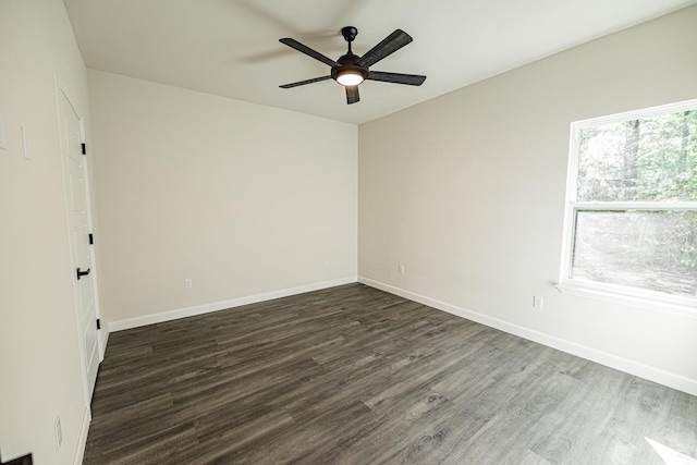 empty room with dark wood-type flooring, a ceiling fan, and baseboards