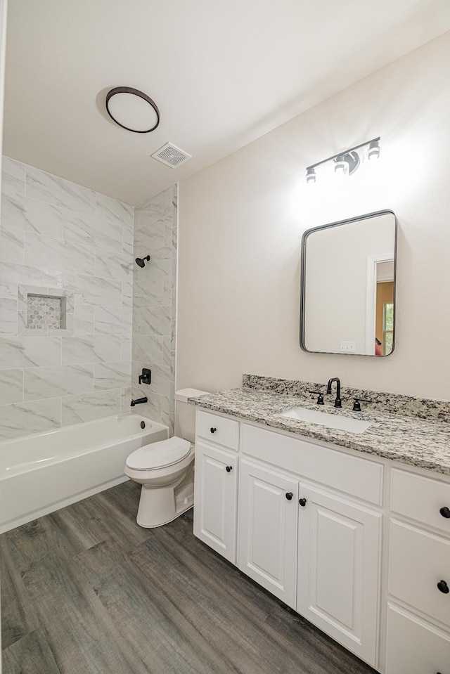 full bath with visible vents, toilet, vanity, shower / tub combination, and wood finished floors