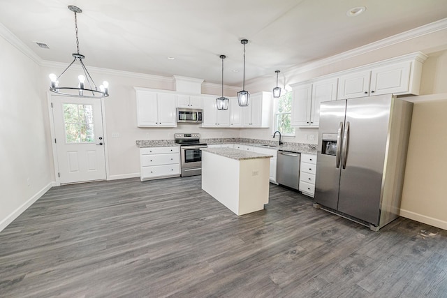 kitchen with stainless steel appliances, white cabinetry, decorative light fixtures, and a center island