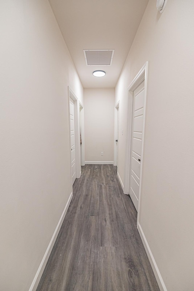 hall with baseboards, visible vents, dark wood finished floors, and attic access