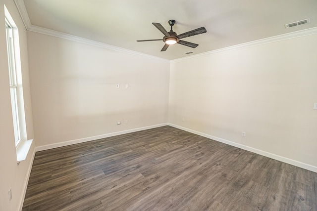 spare room featuring ornamental molding, baseboards, visible vents, and dark wood-type flooring