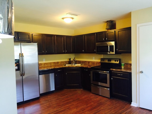 kitchen with dark wood-style flooring, visible vents, a sink, dark countertops, and stainless steel appliances