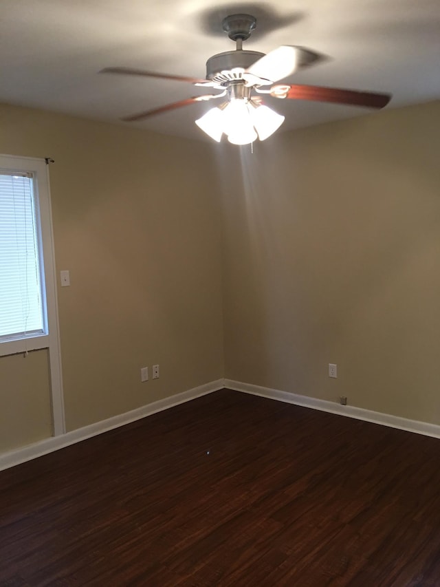 unfurnished room featuring ceiling fan, baseboards, and dark wood finished floors