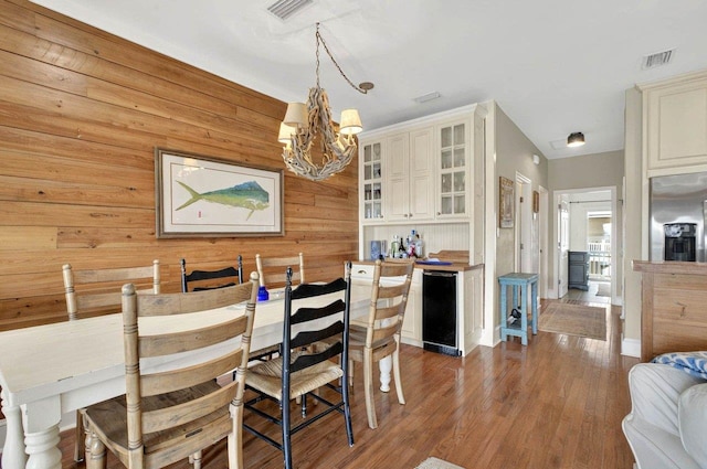 dining space featuring a chandelier, wooden walls, wood finished floors, and baseboards