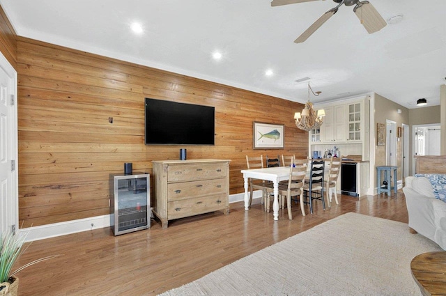 living room featuring wine cooler, wooden walls, a chandelier, baseboards, and recessed lighting