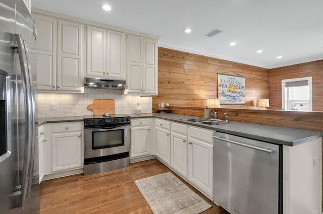 kitchen with stainless steel appliances, under cabinet range hood, a sink, dark countertops, and recessed lighting