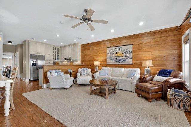 living room with wooden walls, ceiling fan, recessed lighting, and wood finished floors