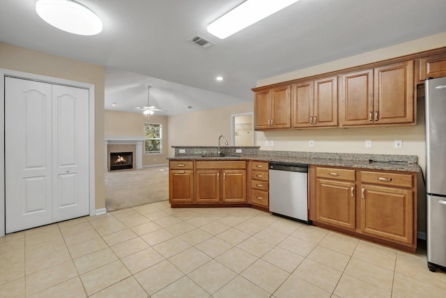 kitchen featuring visible vents, appliances with stainless steel finishes, brown cabinetry, a sink, and a peninsula