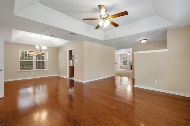 spare room featuring baseboards, visible vents, a tray ceiling, and wood finished floors