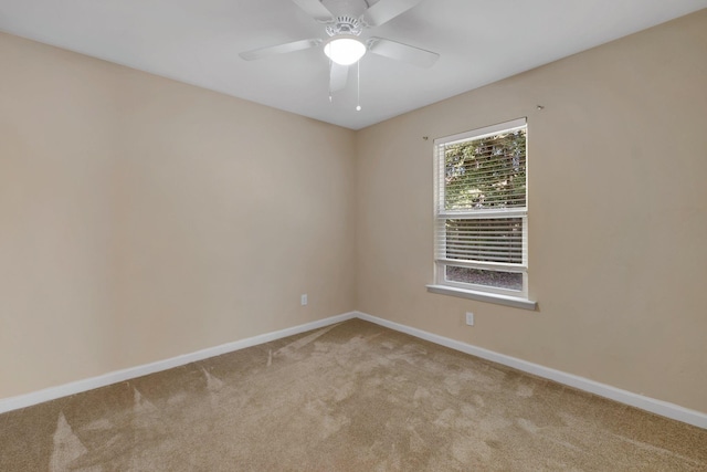 carpeted spare room featuring baseboards and a ceiling fan