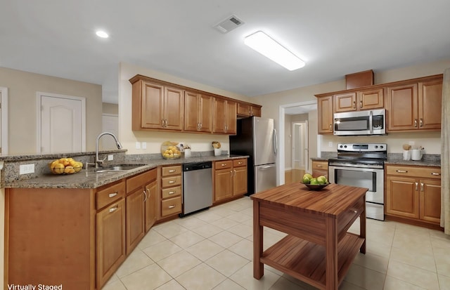 kitchen with visible vents, appliances with stainless steel finishes, a peninsula, a sink, and light tile patterned flooring