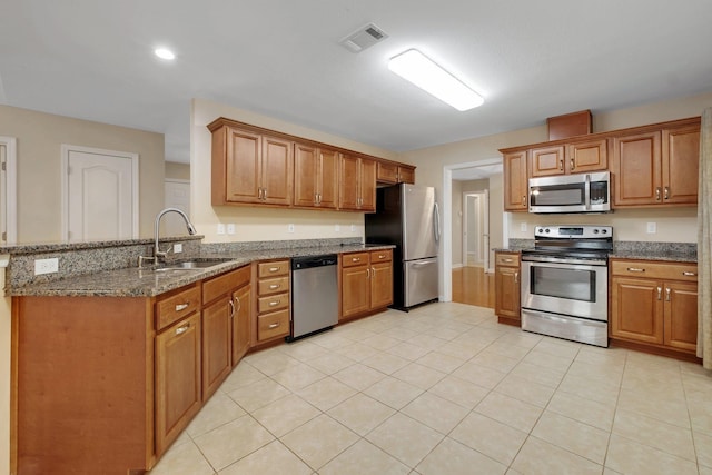 kitchen with a peninsula, a sink, visible vents, appliances with stainless steel finishes, and brown cabinets