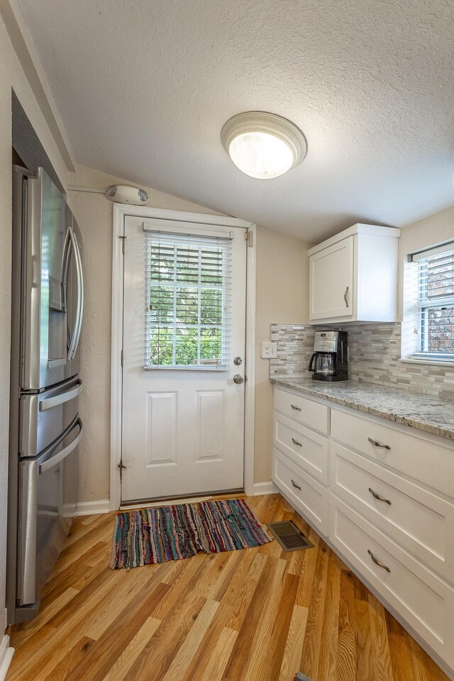 doorway to outside featuring a textured ceiling, light wood-type flooring, and a healthy amount of sunlight