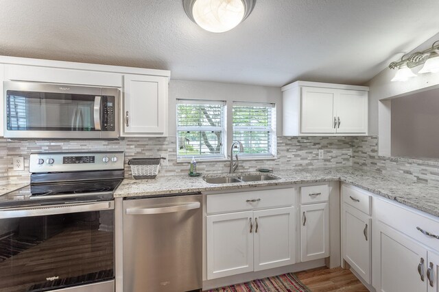 kitchen with stainless steel appliances, white cabinetry, sink, and tasteful backsplash