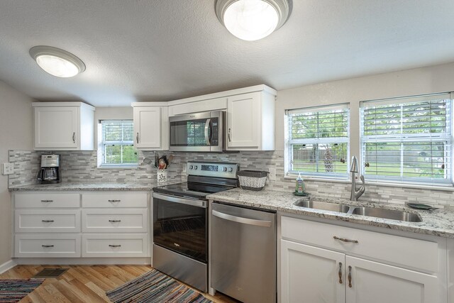 kitchen featuring white cabinets, decorative backsplash, stainless steel appliances, and sink