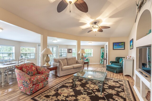 living room with light hardwood / wood-style floors, ceiling fan, and vaulted ceiling