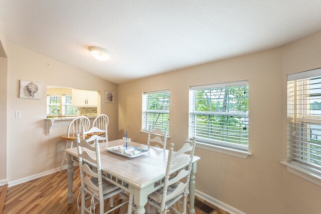 dining space with light wood-type flooring and vaulted ceiling