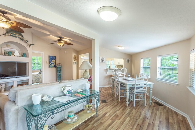 living room featuring ceiling fan, light wood-type flooring, and lofted ceiling