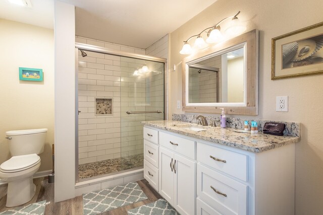 bathroom with walk in shower, vanity, hardwood / wood-style flooring, and toilet