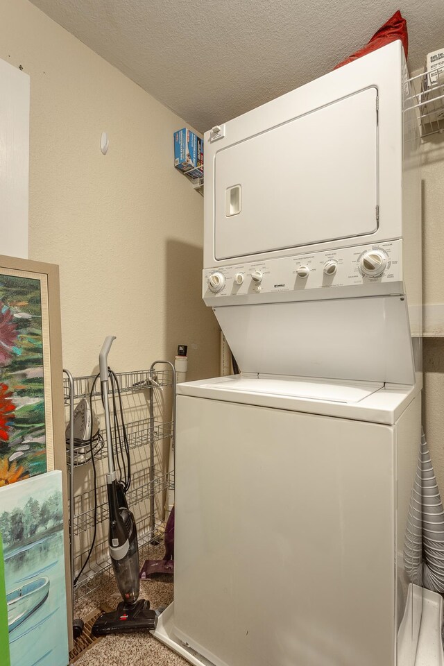 washroom with a textured ceiling, carpet flooring, and stacked washer / drying machine