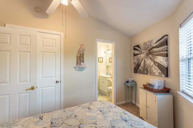 bedroom with a closet, ensuite bath, light carpet, vaulted ceiling, and ceiling fan