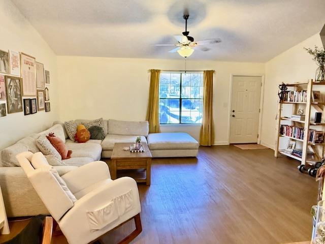 living room featuring wood-type flooring, lofted ceiling, and ceiling fan