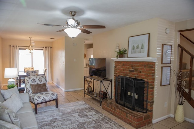 living room featuring ceiling fan, a brick fireplace, and light tile patterned floors