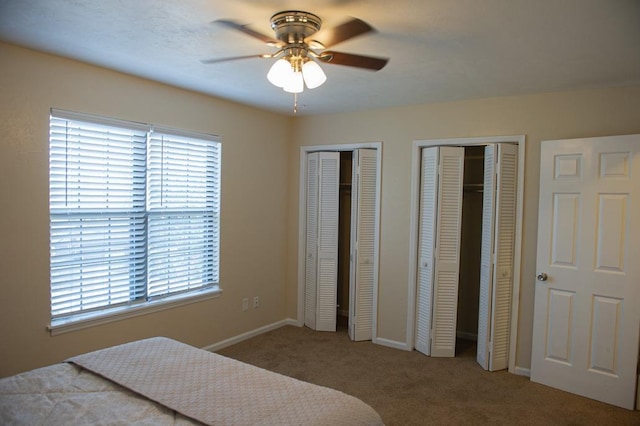 carpeted bedroom with two closets and ceiling fan