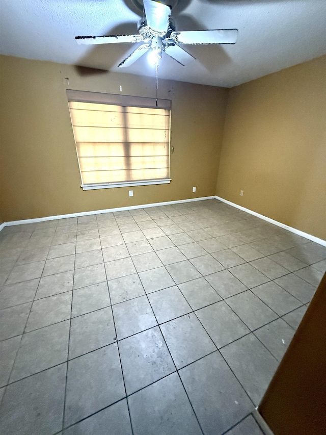 spare room featuring a ceiling fan and baseboards