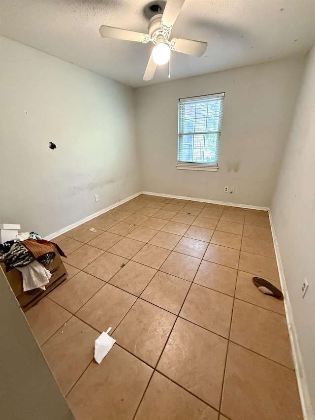 unfurnished room with baseboards, a ceiling fan, a textured ceiling, and light tile patterned flooring