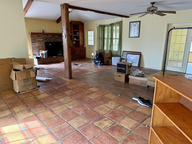 living room featuring lofted ceiling with beams, ceiling fan, wood finished floors, a textured ceiling, and a brick fireplace