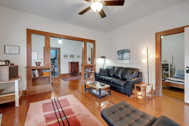 living room featuring ceiling fan, ornate columns, and light wood-type flooring