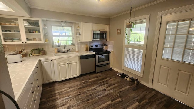 kitchen featuring dark wood-type flooring, tile counters, white cabinets, stainless steel appliances, and a sink