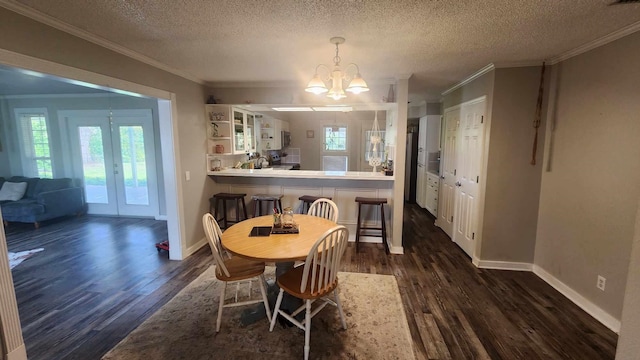 dining area with french doors, crown molding, an inviting chandelier, and dark wood-style flooring